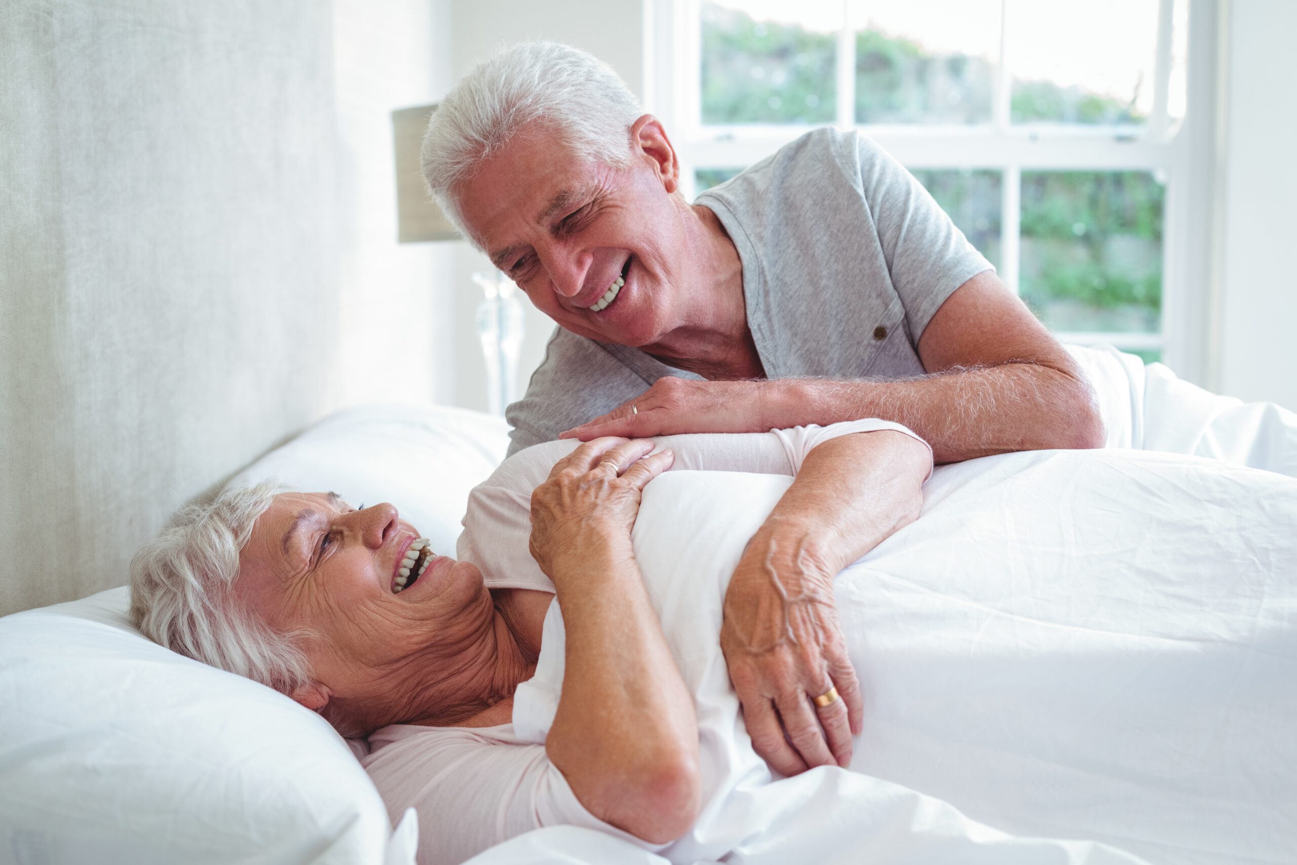 Smiling senior couple relaxing on bed at home