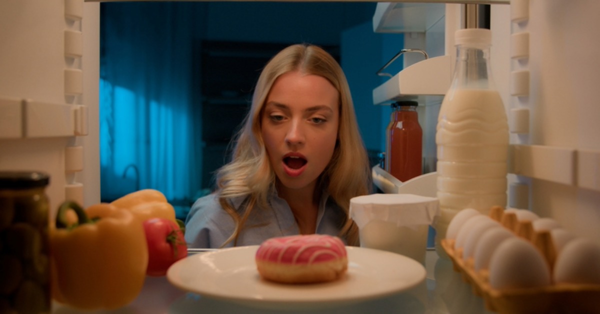 omeone opening the fridge late at night, eyeing a piece of cake, or surrounded by snacks.